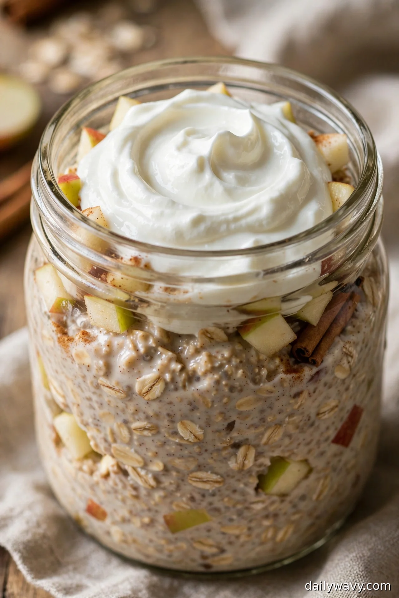 Apple cinnamon overnight oats with a thick Greek yogurt swirl, apple chunks and cinnamon sticks