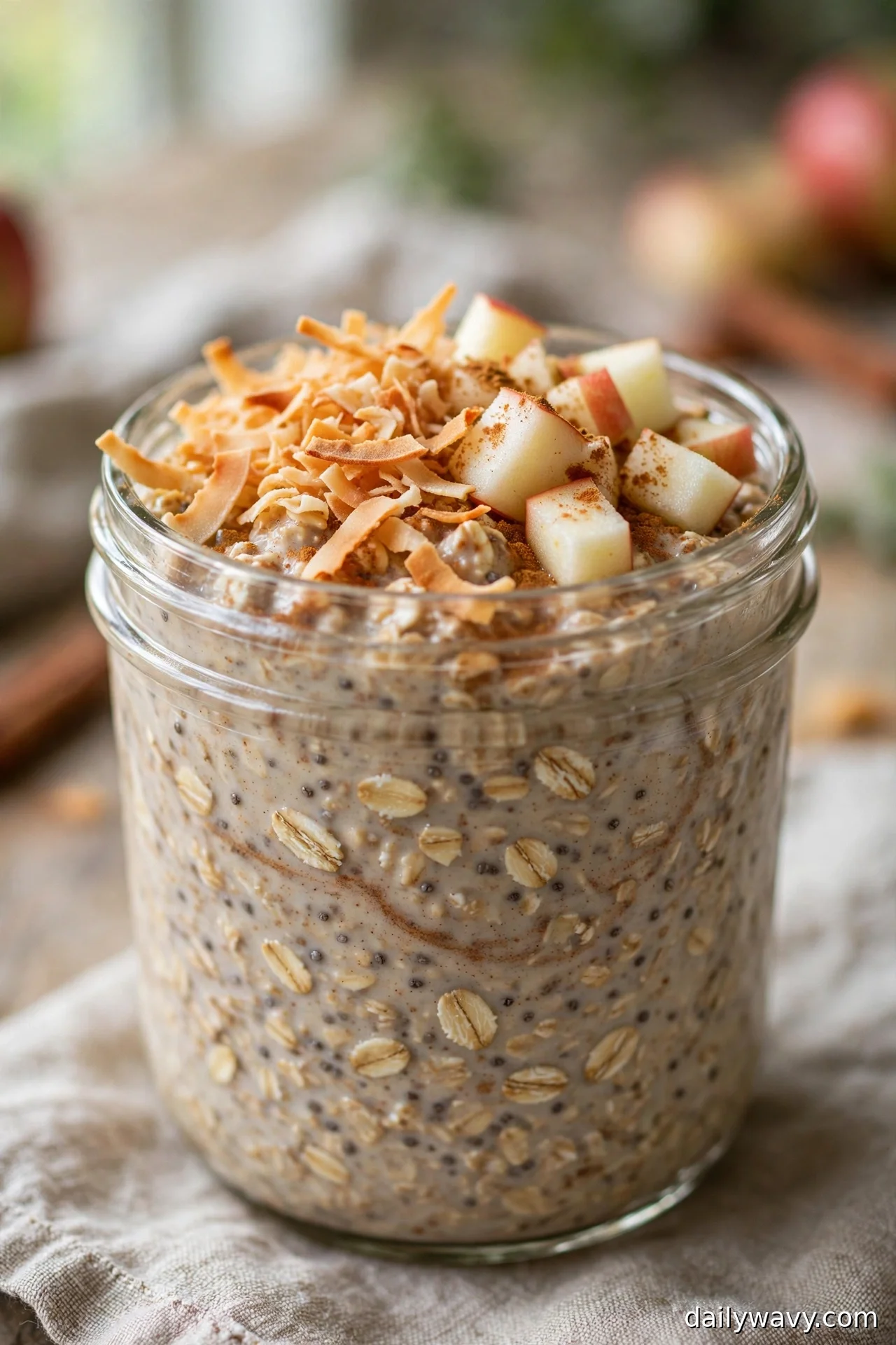 Apple cinnamon overnight oats topped with toasted coconut flakes and diced apple