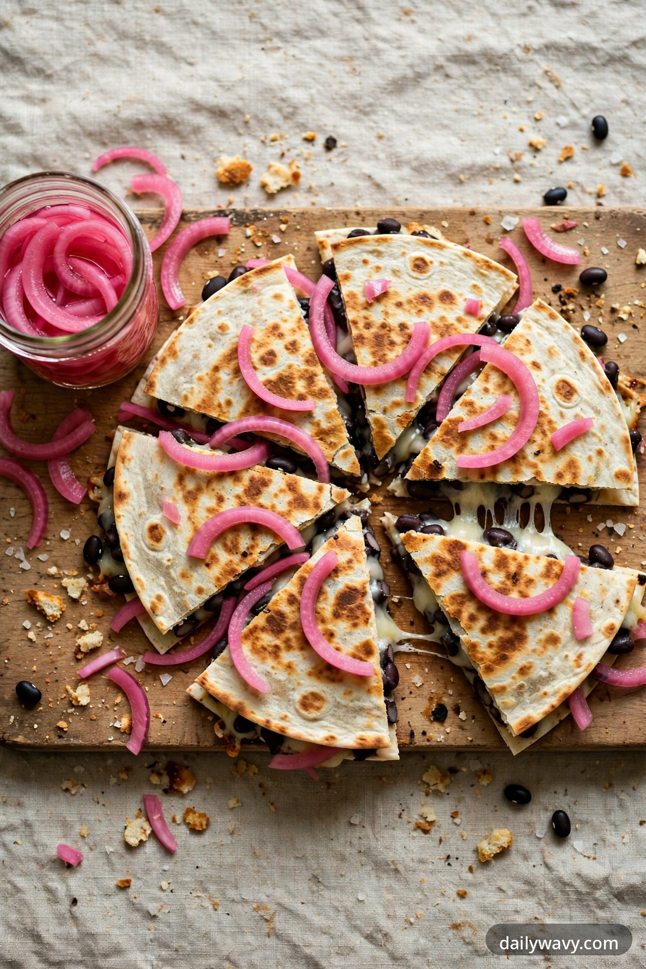 Black bean quesadilla with pickled onions, cut into wedges on a plate