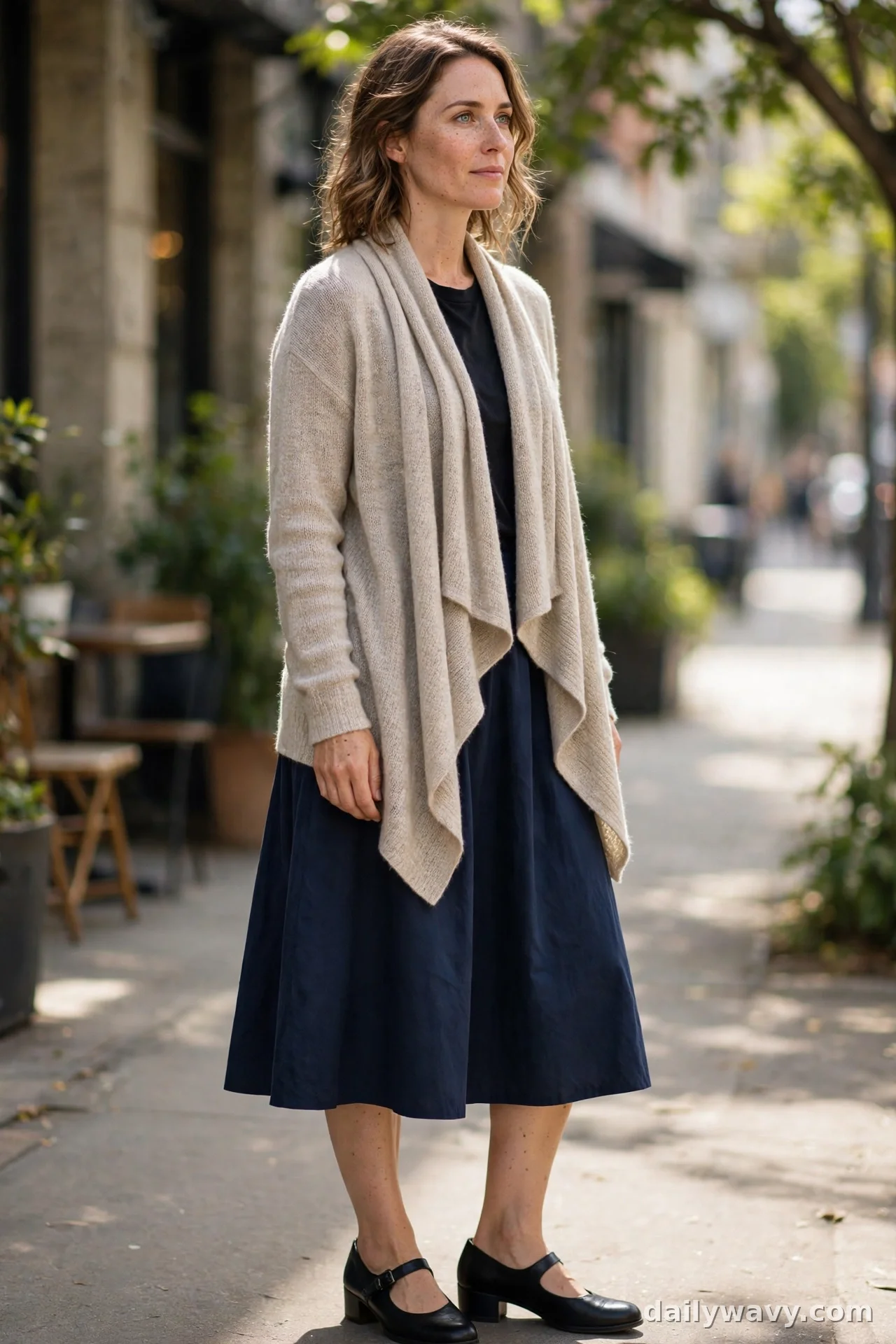 Woman in oatmeal waterfall cardigan with navy A-line midi skirt and black Mary Jane heels