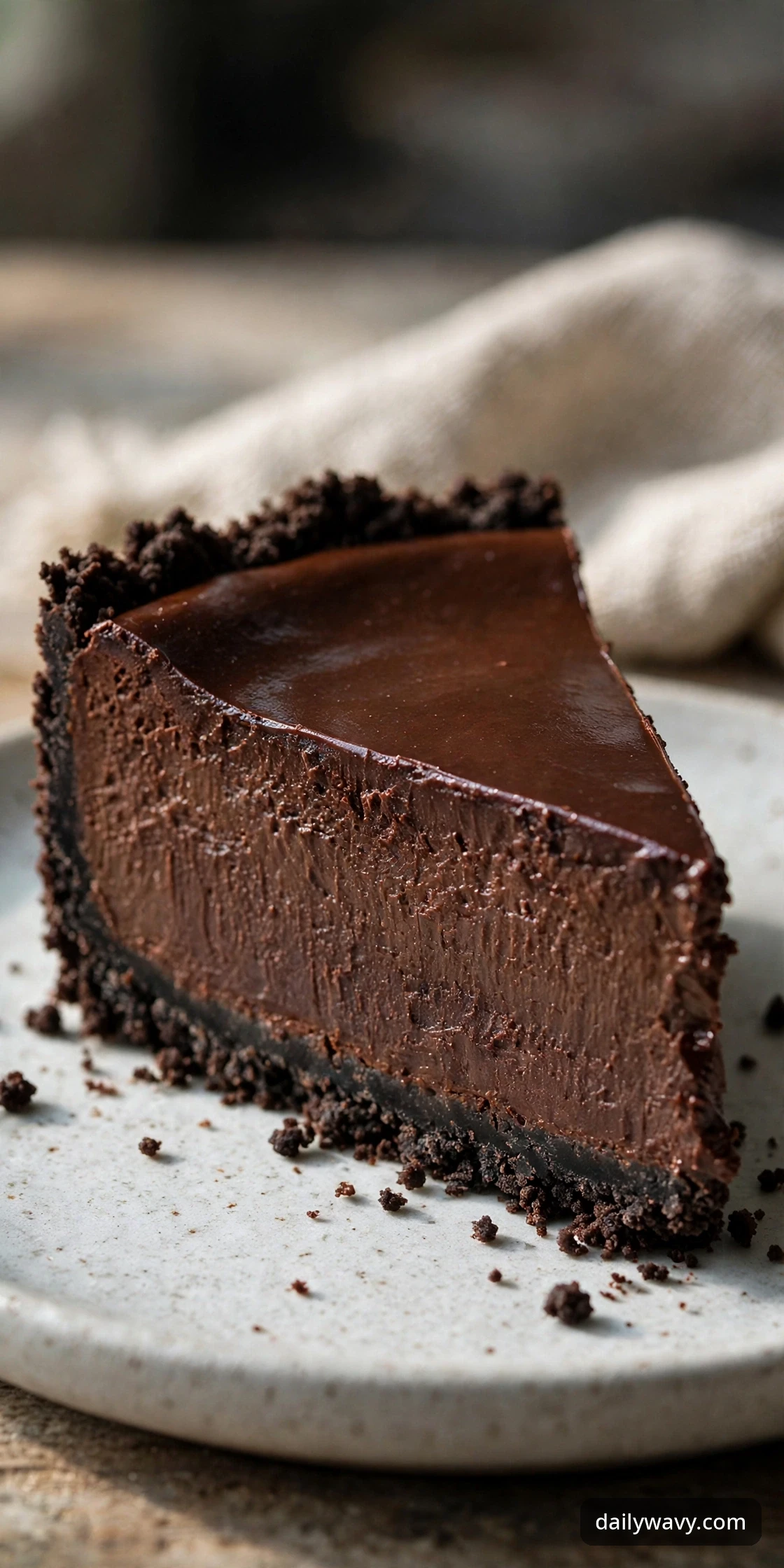 Chocolate cheesecake slice with a chocolate cookie crust showing the set filling