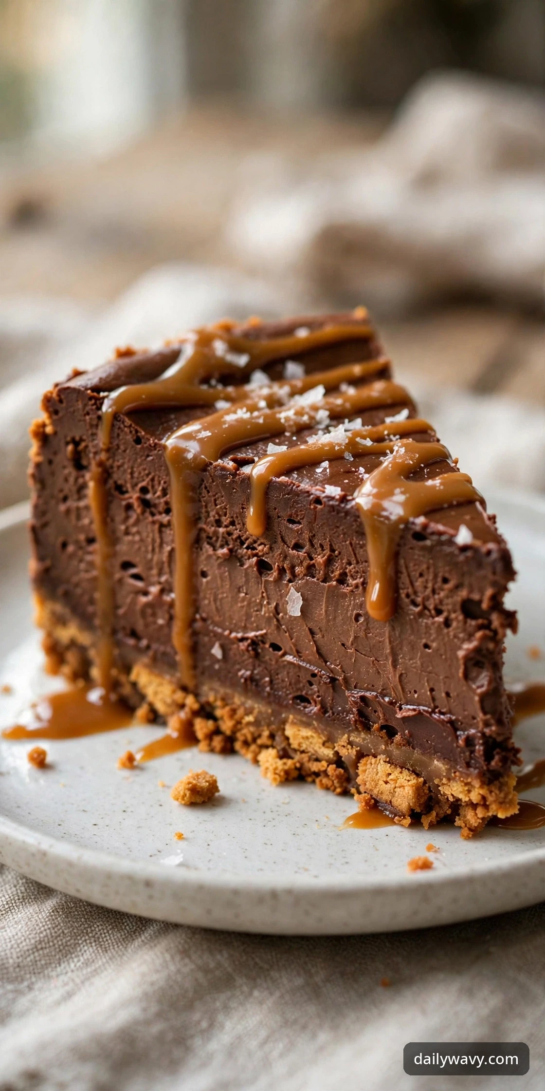 Chocolate cheesecake slice with a caramel biscuit base drizzled with caramel