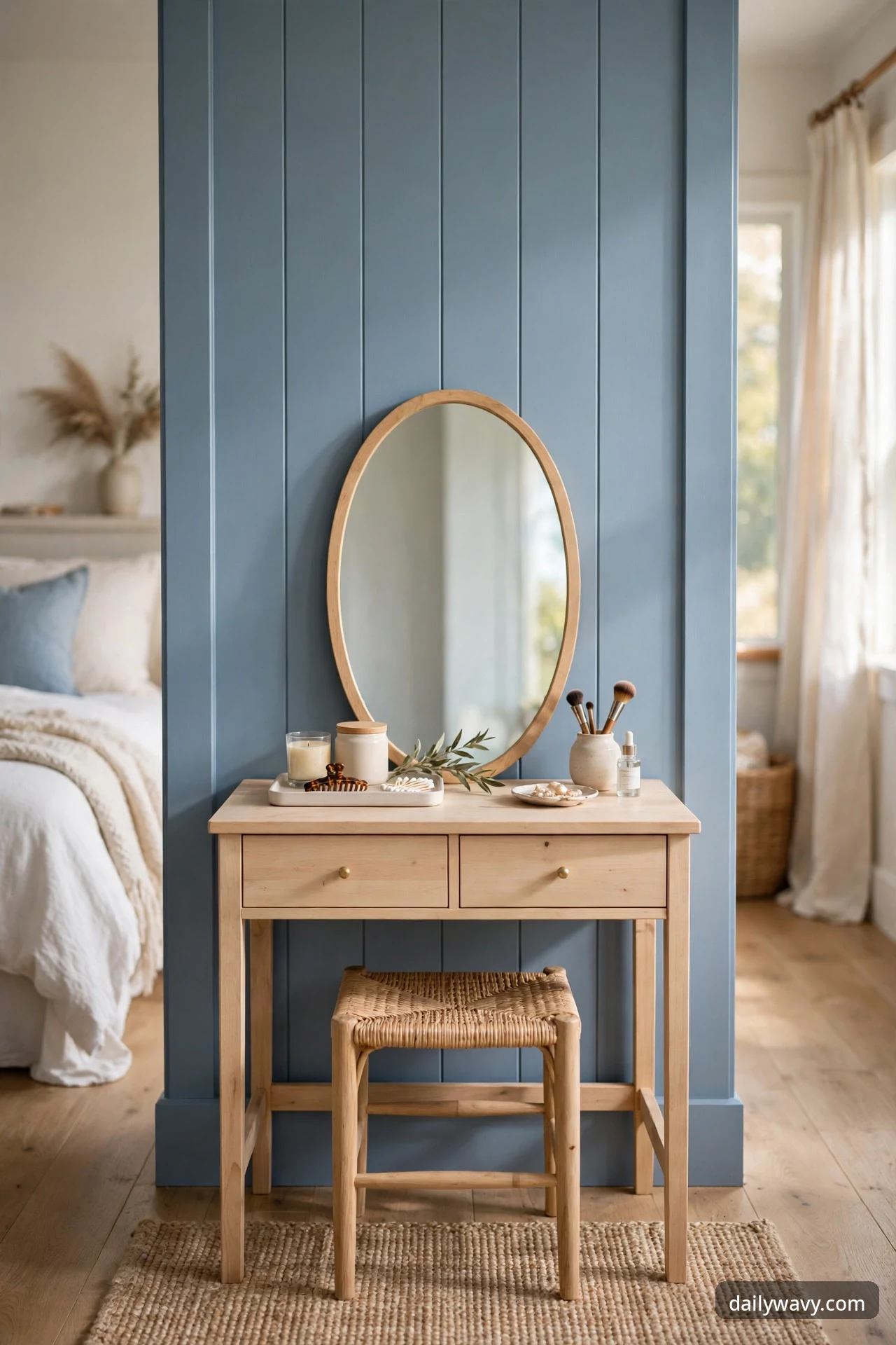 Light-wood writing desk with two drawers and a woven stool, styled as a vanity with an oval mirror leaning behind it