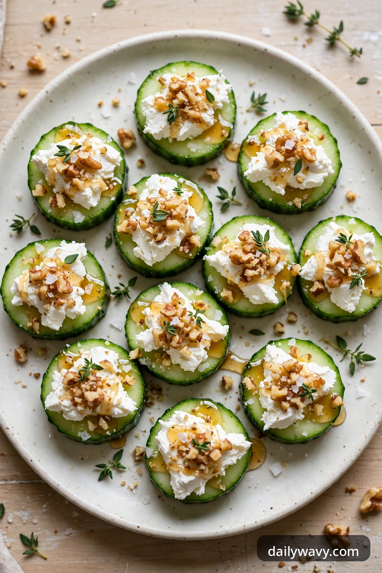 Cucumber rounds spread with tangy goat cheese, chopped toasted walnuts, honey drizzle and thyme leaves