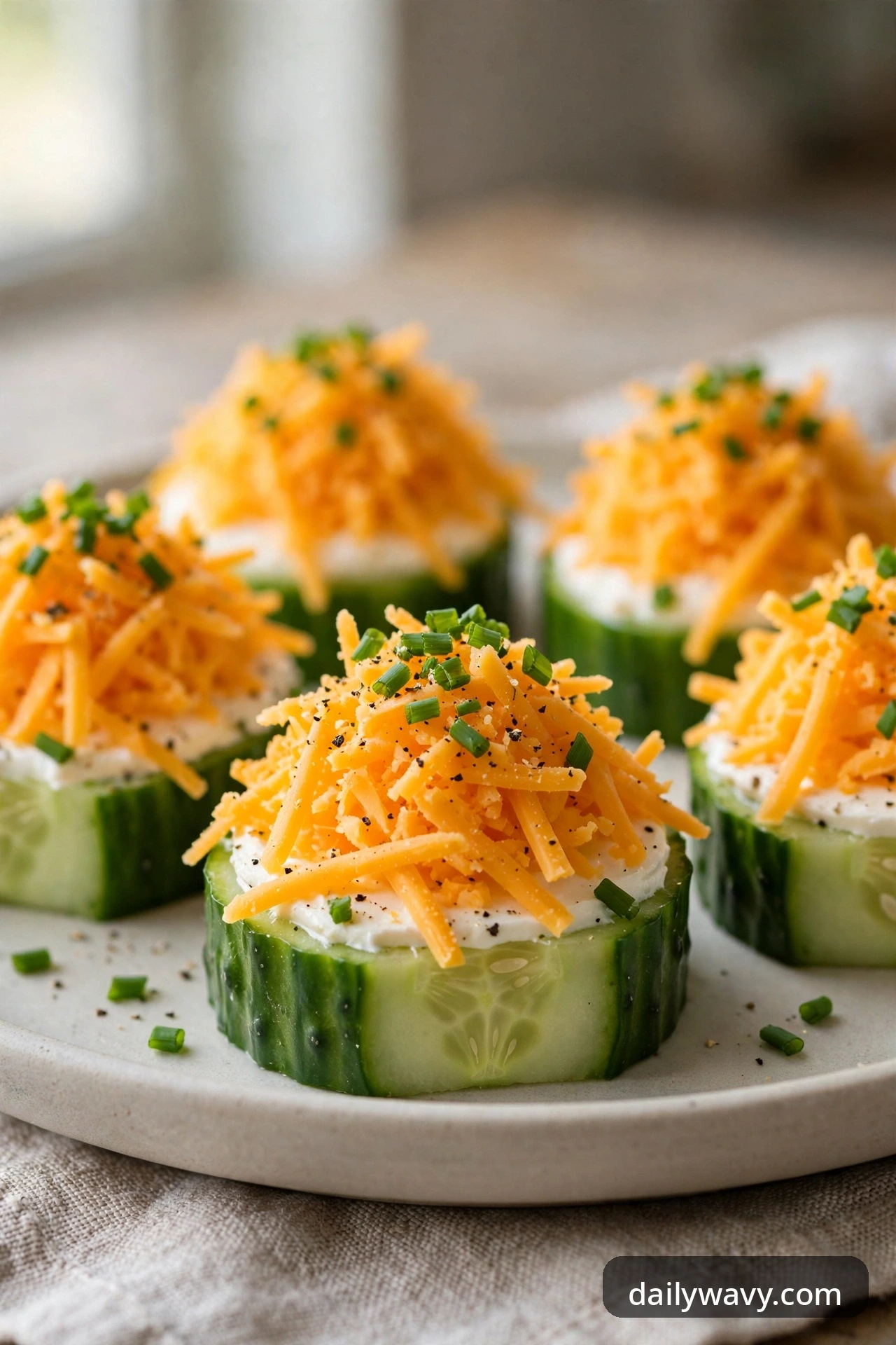 Cucumber rounds with cream cheese, shredded sharp cheddar, snipped chives and black pepper