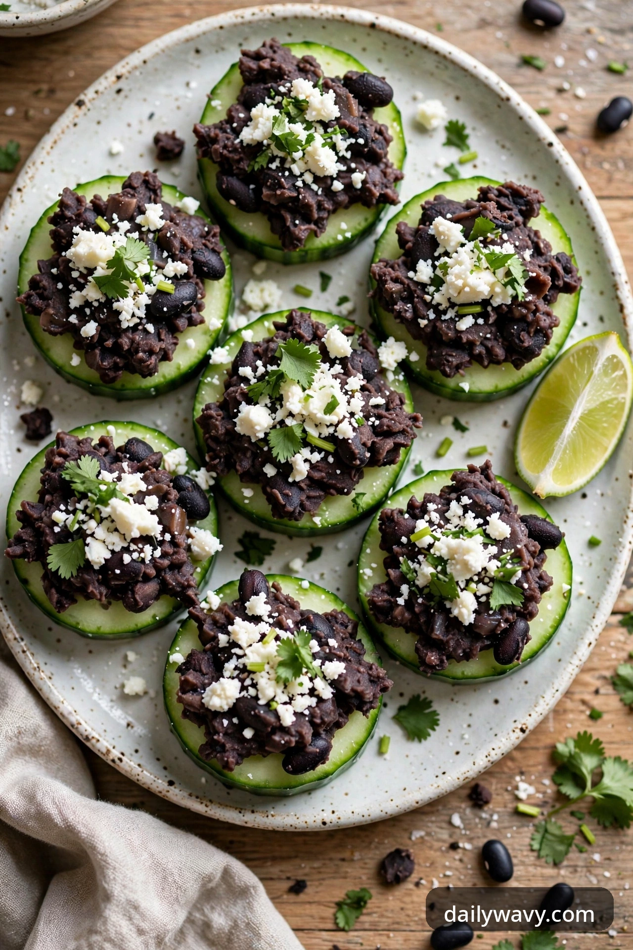 Cucumber rounds with rough-mashed black bean spread, crumbled cotija, chopped cilantro and a lime wedge