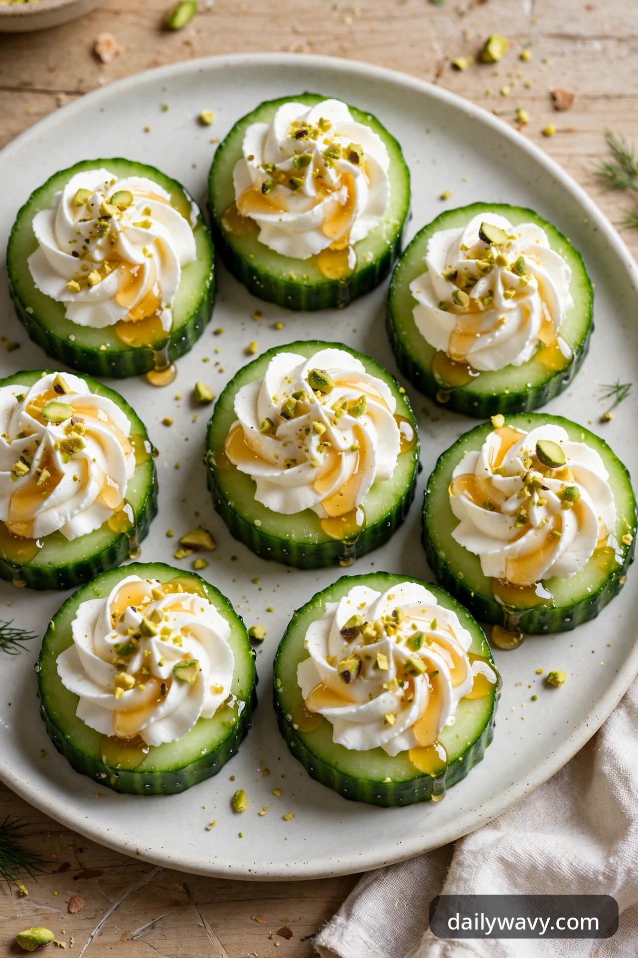 Cucumber rounds with piped swirls of whipped feta, glossy honey drizzle and crushed pistachios