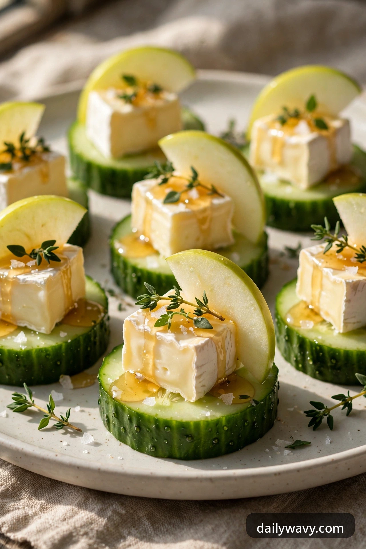 Cucumber rounds with a cube of creamy brie, a thin crisp apple slice, honey drizzle and thyme