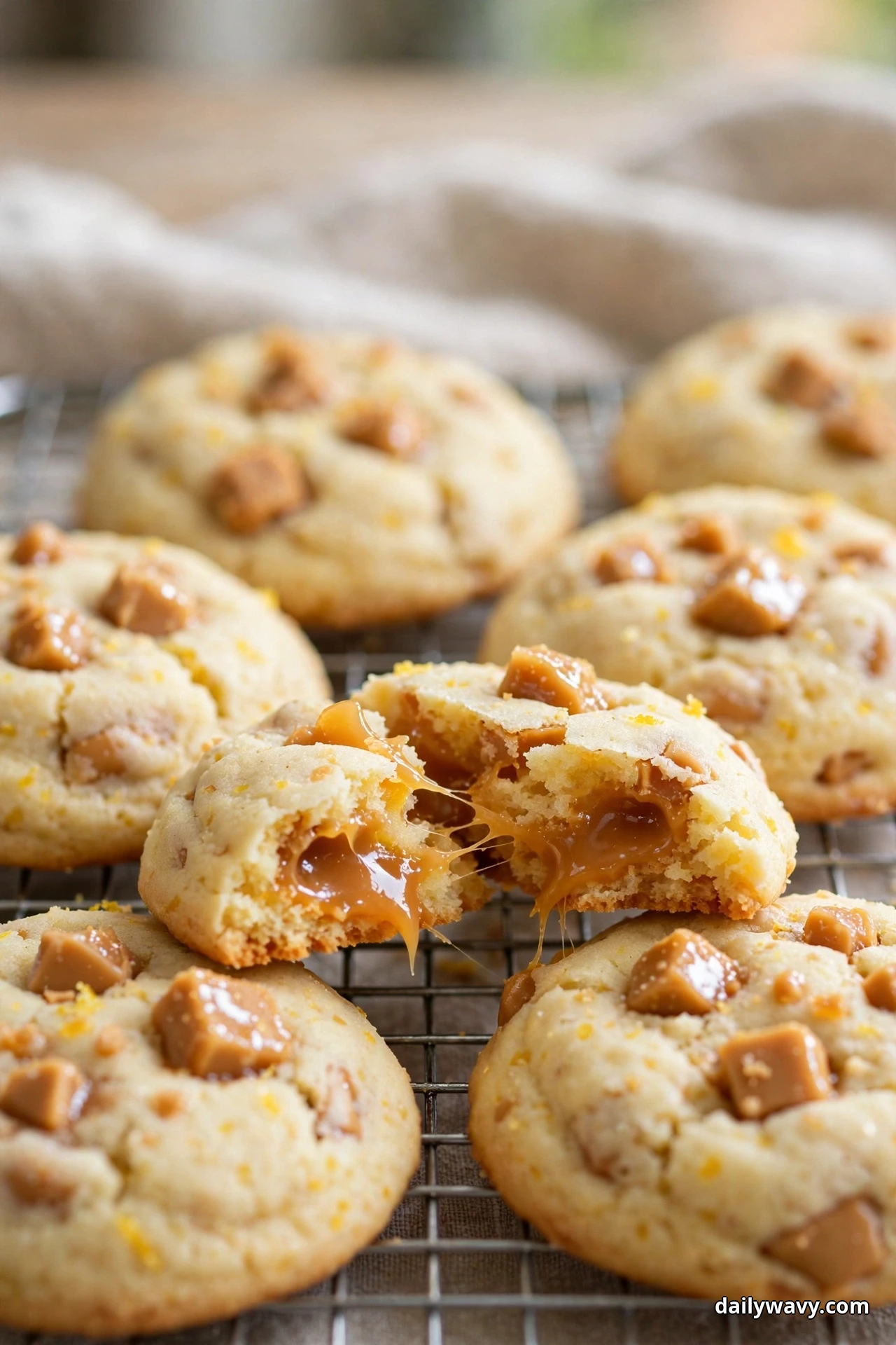 Lemon cookies studded with chunks of toffee cool on a wire rack, one broken apart with melted toffee stretching between the halves