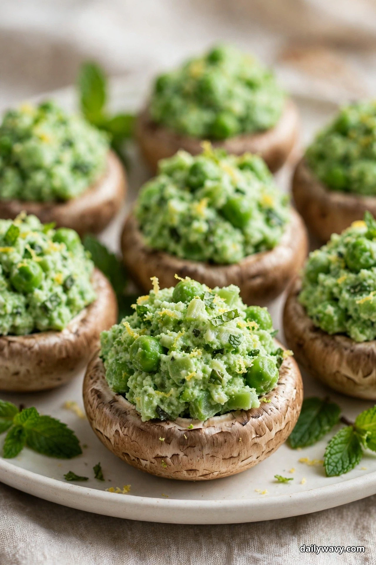 A close view shows mushroom caps heaped with a textured pea and ricotta filling flecked with mint and lemon zest