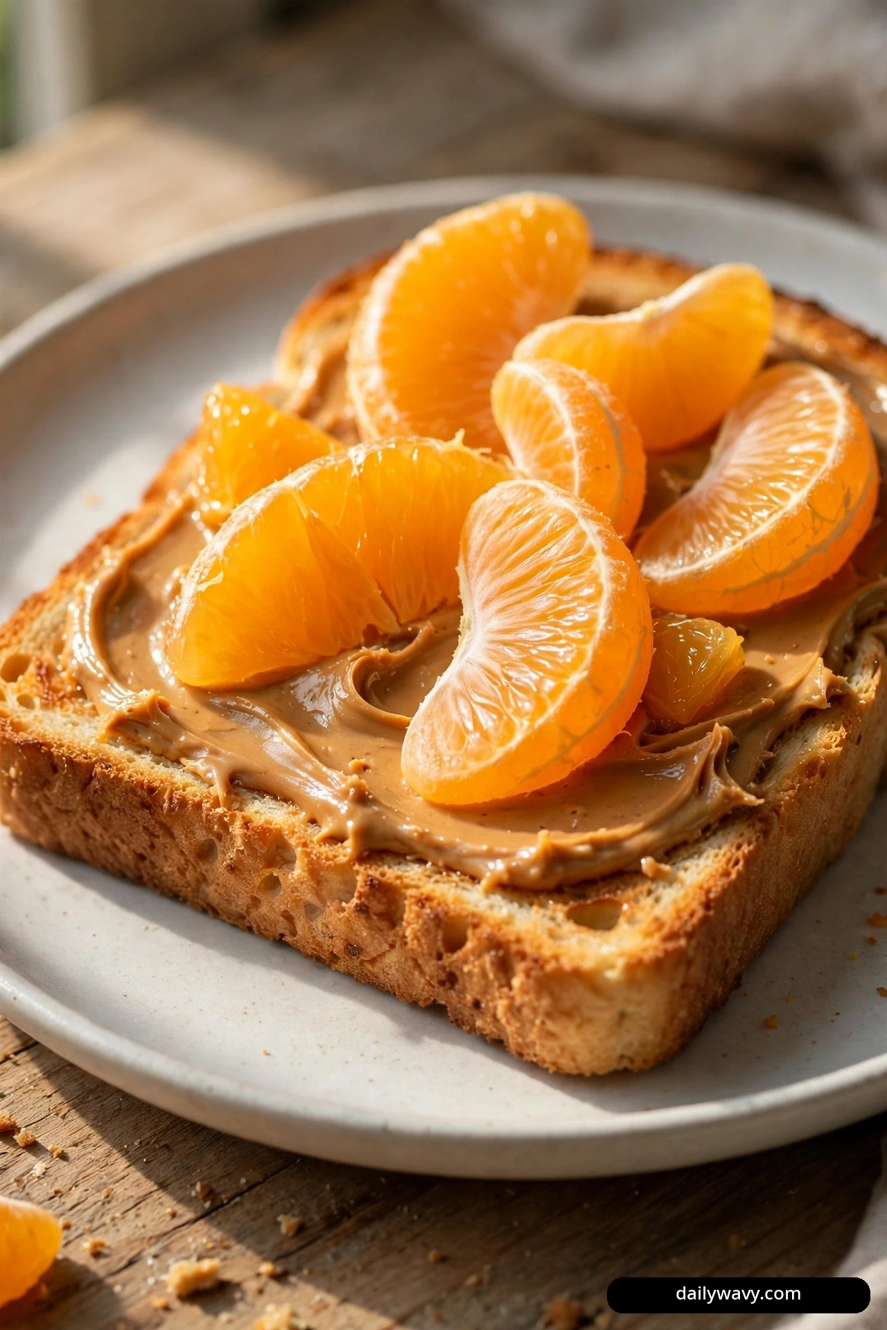 A close view shows a slice of whole wheat toast spread with peanut butter and piled with fresh orange segments.