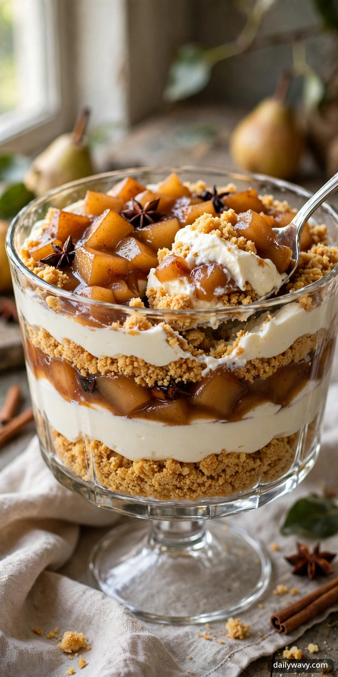 Layered pear biscuit dessert with cream and spiced pears in a trifle bowl