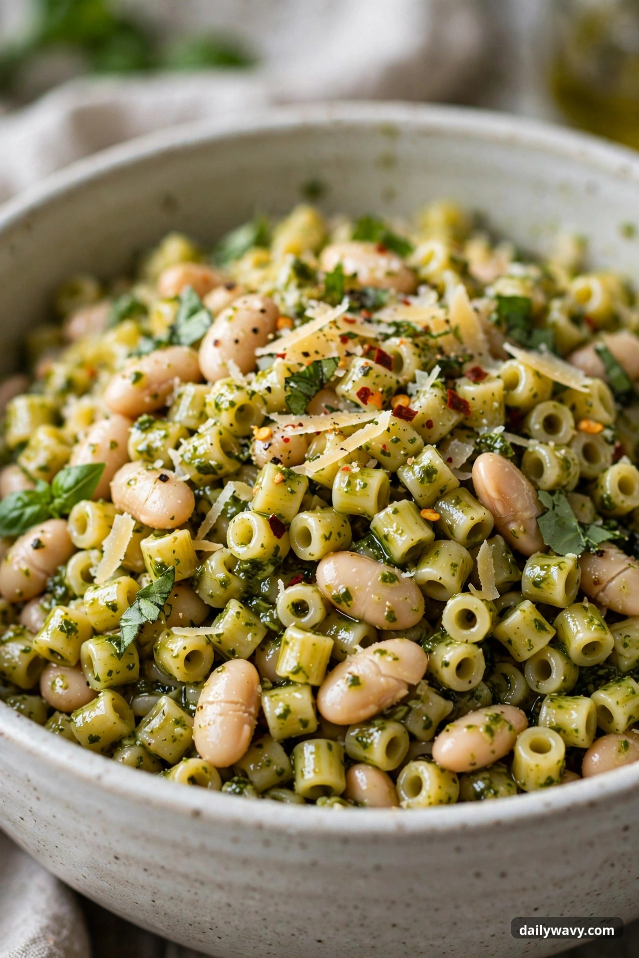 Pesto pasta salad with ditalini and white beans in a mixing bowl