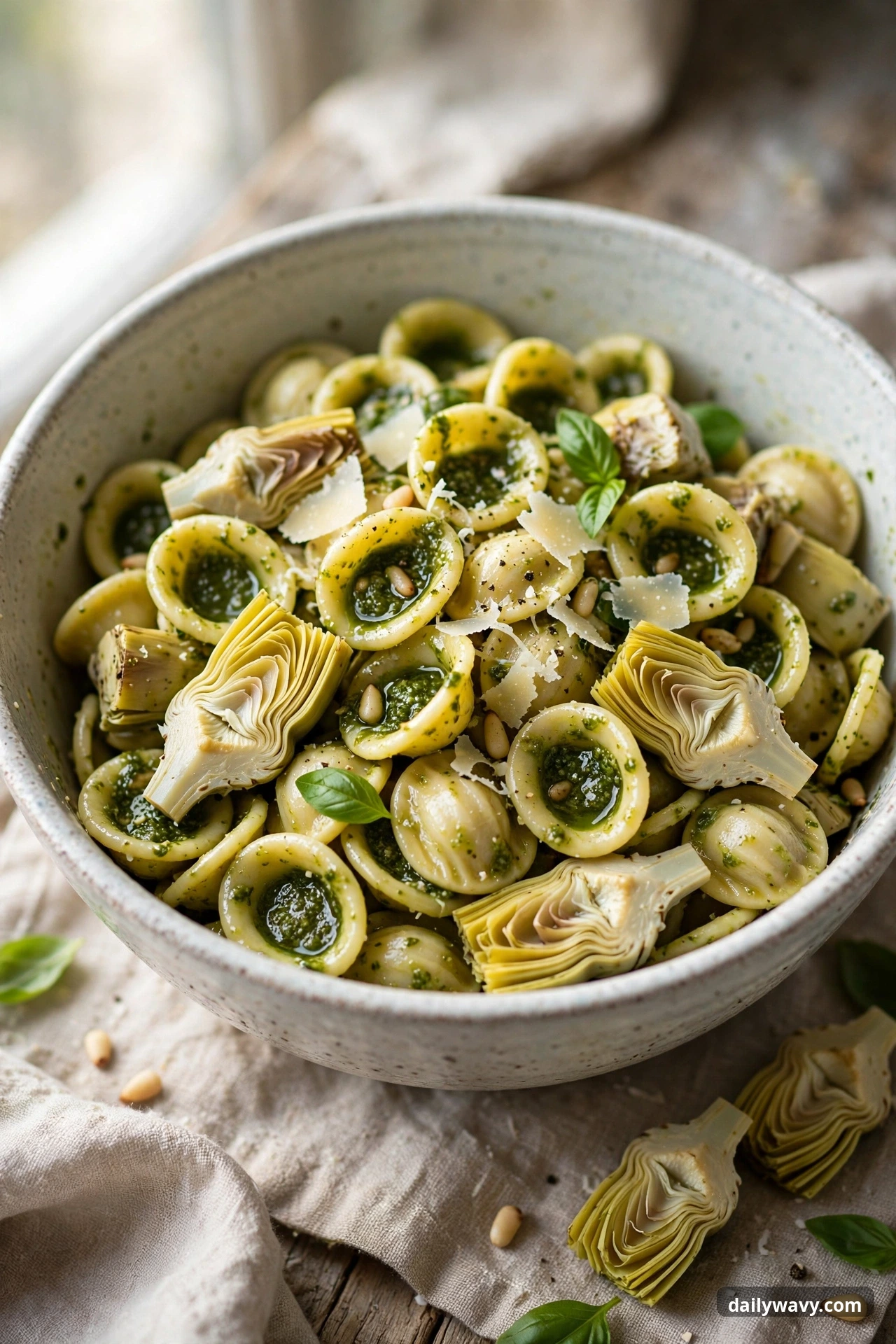 Pesto pasta salad with orecchiette and artichokes in a mixing bowl