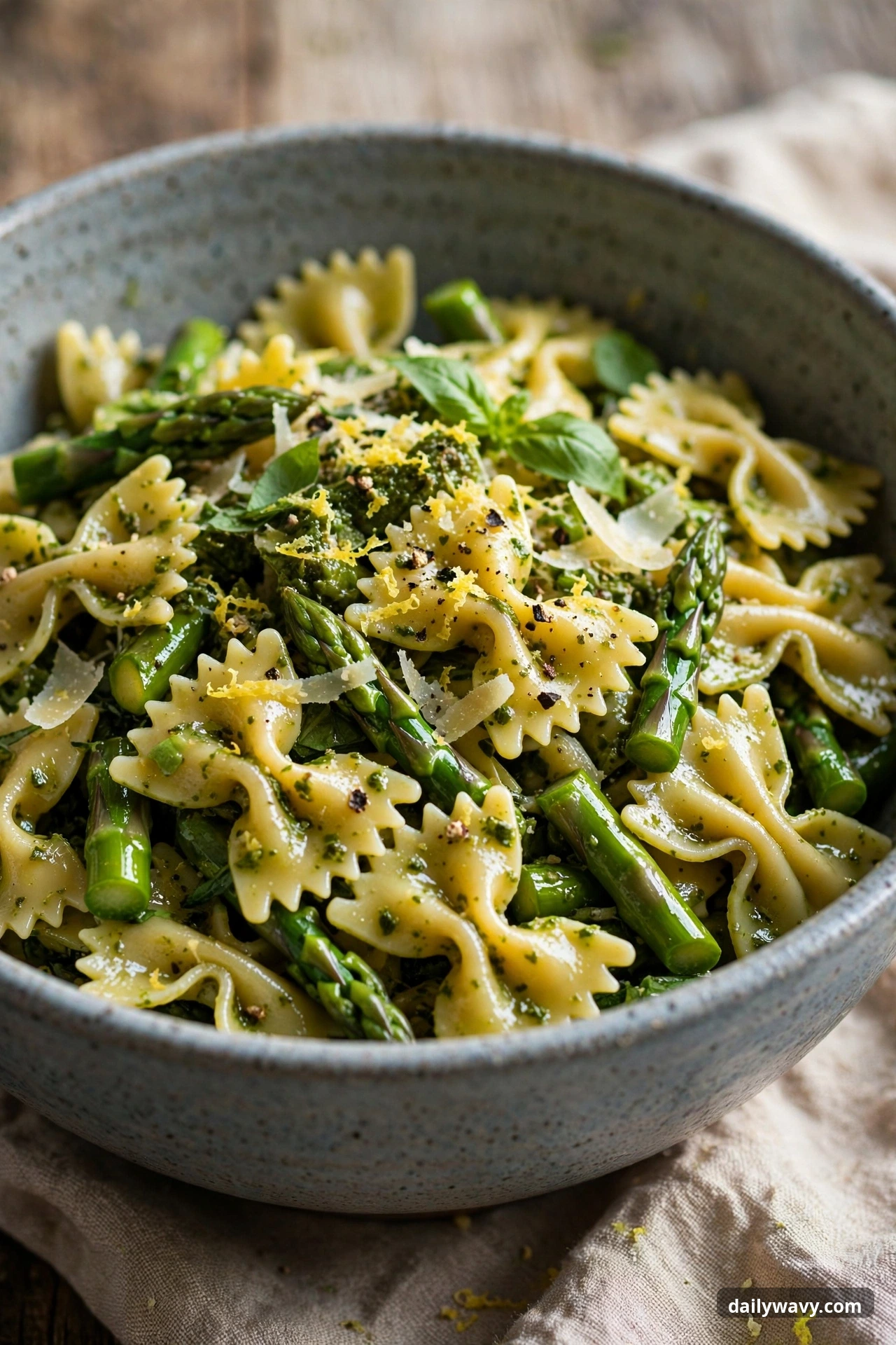 Pesto pasta salad with farfalle and asparagus in a mixing bowl
