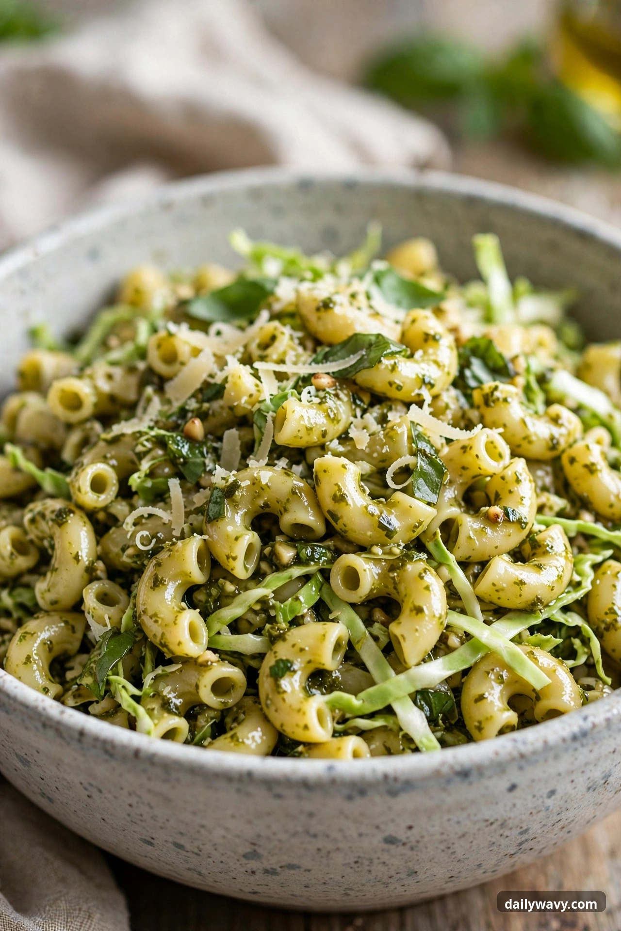 Pesto pasta salad with elbow pasta and cabbage in a mixing bowl