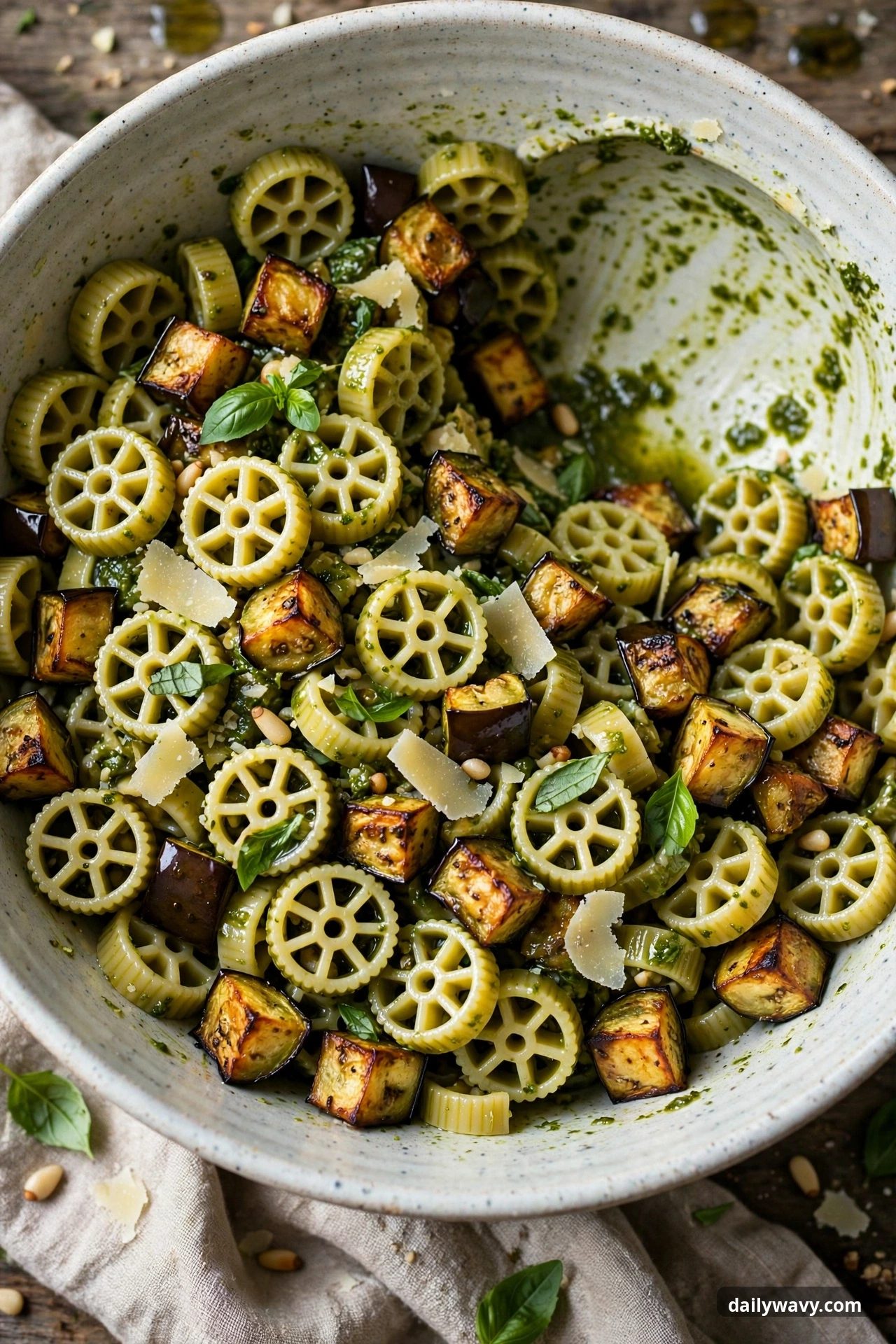Pesto pasta salad with rotelle and roasted eggplant in a mixing bowl