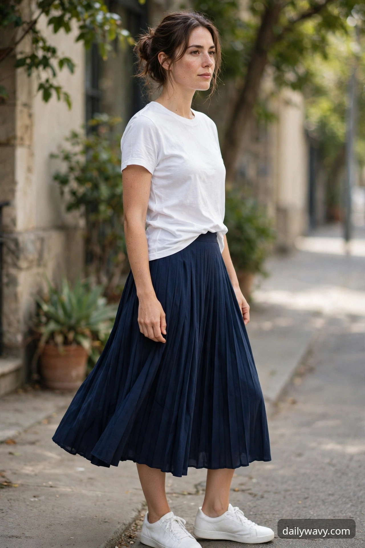 Woman wearing a pleated skirt, a plain tee and white sneakers